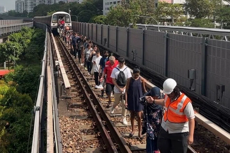 About 850 commuters on board a stalled train near Clementi MRT station safely disembarking on the tracks and being guided back to the station platform. 