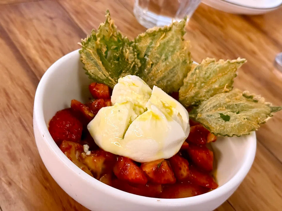 Salad of burrata cheese, strawberries and tomatoes in kimchi sauce.