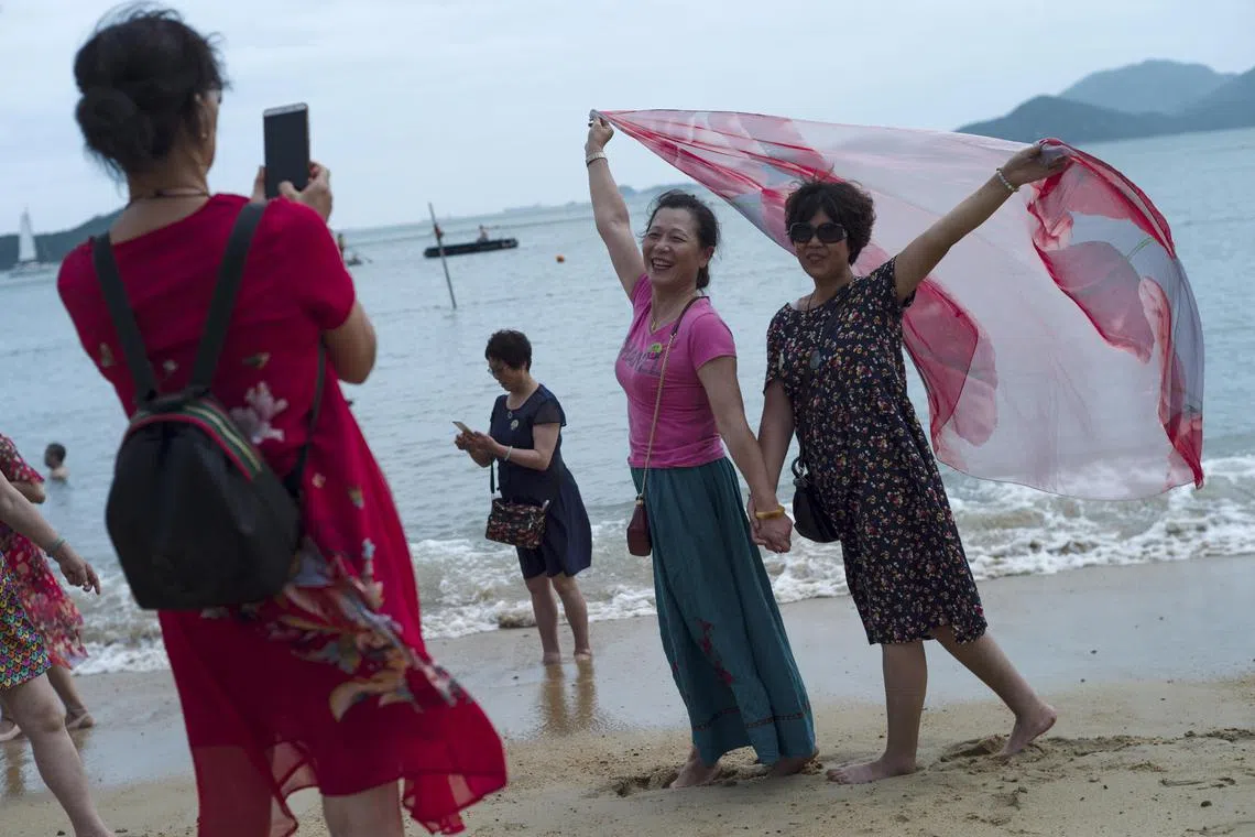 Mainland Chinese tourists pose for photographs on a beach at Repulse Bay in Hong Kong, China, July 16, 2018. 
