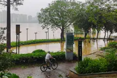 A cyclist peddles past flood waters near a river in Qingyuan City, Guangdong, China on April 21, 2024. 