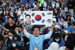 Supporters of Lee Jae-myung, the presidential candidate for South Korea's Democratic Party, react while watching a television report on an exit poll of the presidential election, near the National Assembly in Seoul on Jun 3.