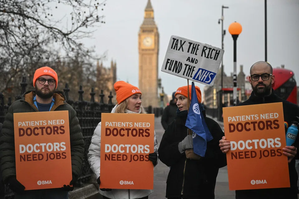Staff members holding placards as they stand on a picket line outside St Thomas' Hospital in central London on Dec 17.