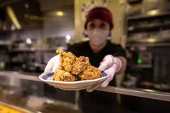 Hiromi Matsumoto serving a plate of karaage, a Japanese style fried chicken at an izakaya bar in Tokyo, March 1, 2023.