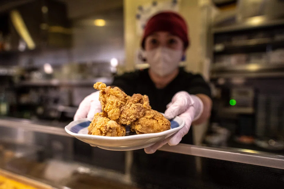 Hiromi Matsumoto serving a plate of karaage, a Japanese style fried chicken at an izakaya bar in Tokyo, March 1, 2023.