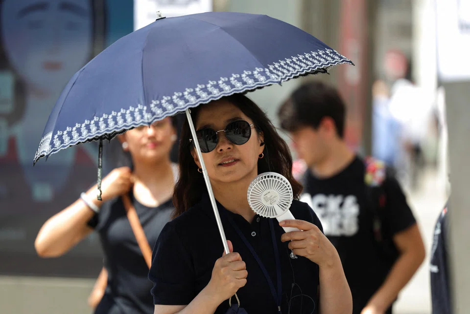 A woman protects herself with an umbrella during a heatwave in Madrid. The world’s listed companies are on track to overshoot their collective carbon budget for staying under the Paris Agreement goal within the next two years.