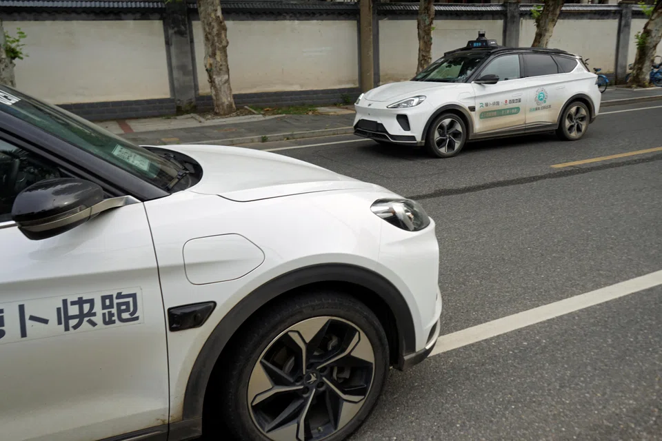A driverless car by Apollo Go going past a parked Apollo Go robotaxi in Wuhan. Baidu's robotaxi service has said that it plans to deploy 1,000 vehicles in Wuhan by year-end and operate in 100 cities by 2030. 