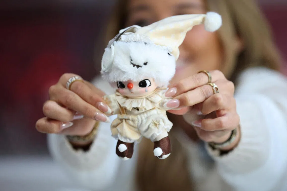 An influencer holds a Labubu Why So Serious Plush Pendant doll during an AliExpress and Pop Mart livestream shopping show on Singles' Day at a pop-up store in London on Nov 11.