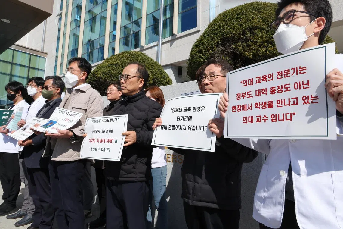 South Korean medical professors holding up signs protesting the government's plan to augment medical student admissions at Jeonbuk National University.  The health ministry this week reiterated that negotiations over the reform plans were out of the question.