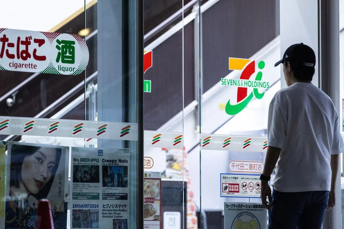 A shopper walks towards a 7-Eleven convenience store, operated by Seven & i Holdings Co., at the company's headquarters in Tokyo, Japan, on Friday, Aug. 23, 2024. Japanese government approval could be a major roadblock in Alimentation Couche-Tard Inc.