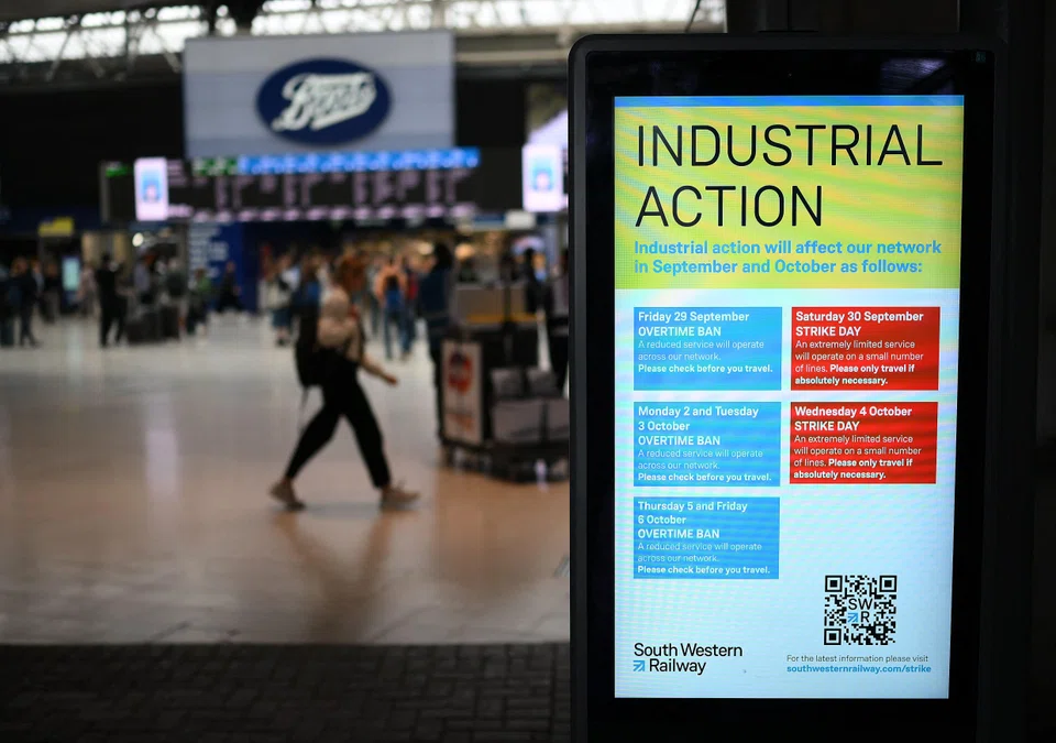 Commuters walk past an announcement board informing people of strike details at Waterloo Station in London on Oct 4, 2023 as train drivers strike over pay. The new legislation will require striking rail workers, ambulance staff and border security staff to maintain certain levels of service.