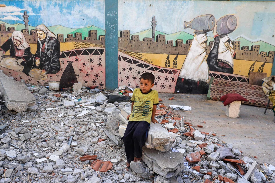 A boy sits above debris at a UN-run school sheltering displaced people after Israeli bombardment in Nuseirat in the central Gaza Strip on July 9, 2024. The Israeli military said its air force had struck "several terrorists" who were using a school "as cover". 