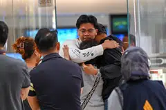 Passengers of Singapore Airlines flight SQ321 from London to Singapore, which made an emergency landing in Bangkok, greet family members upon arrival at Changi Airport in Singapore on May 22. 