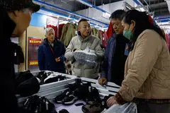 Wankelai store manager Leo Liu promotes a pair of shoes on discount to customers during a flash sale in Beijing, China, Feb 27, 2025. 