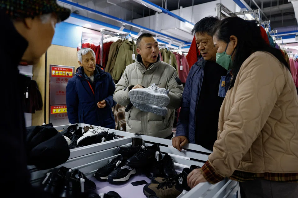 Wankelai store manager Leo Liu promotes a pair of shoes on discount to customers during a flash sale in Beijing, China, Feb 27, 2025. 