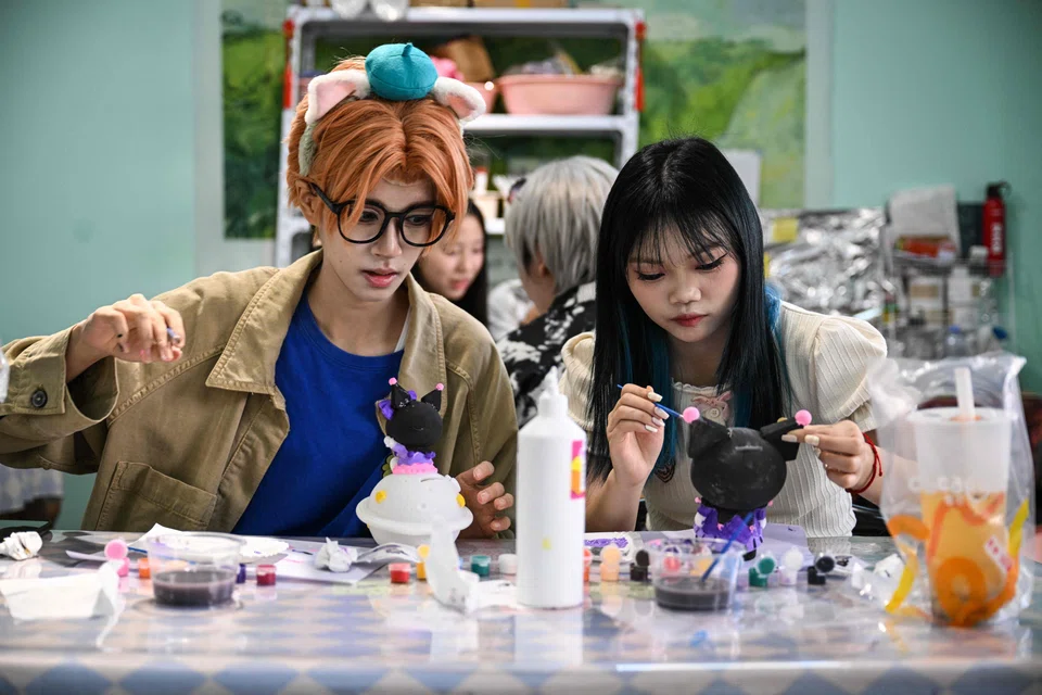 Cosplayer Xu Yunting (left), dressed as Jesse, a male character from the video game 'Light and Night', and Feng Xinyu visiting a crafts shop during their 'cos commissioning' date in Shanghai.