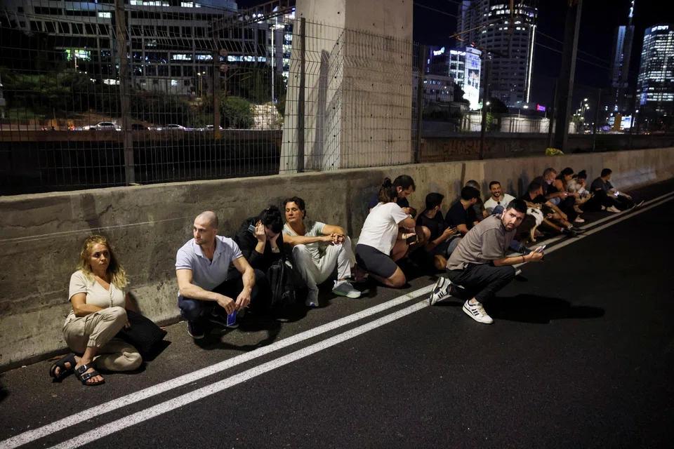 People taking cover by the side of a road in Tel Aviv as a siren sounds, after Iran fired a salvo of ballistic missiles at Israel on Oct 1. 
