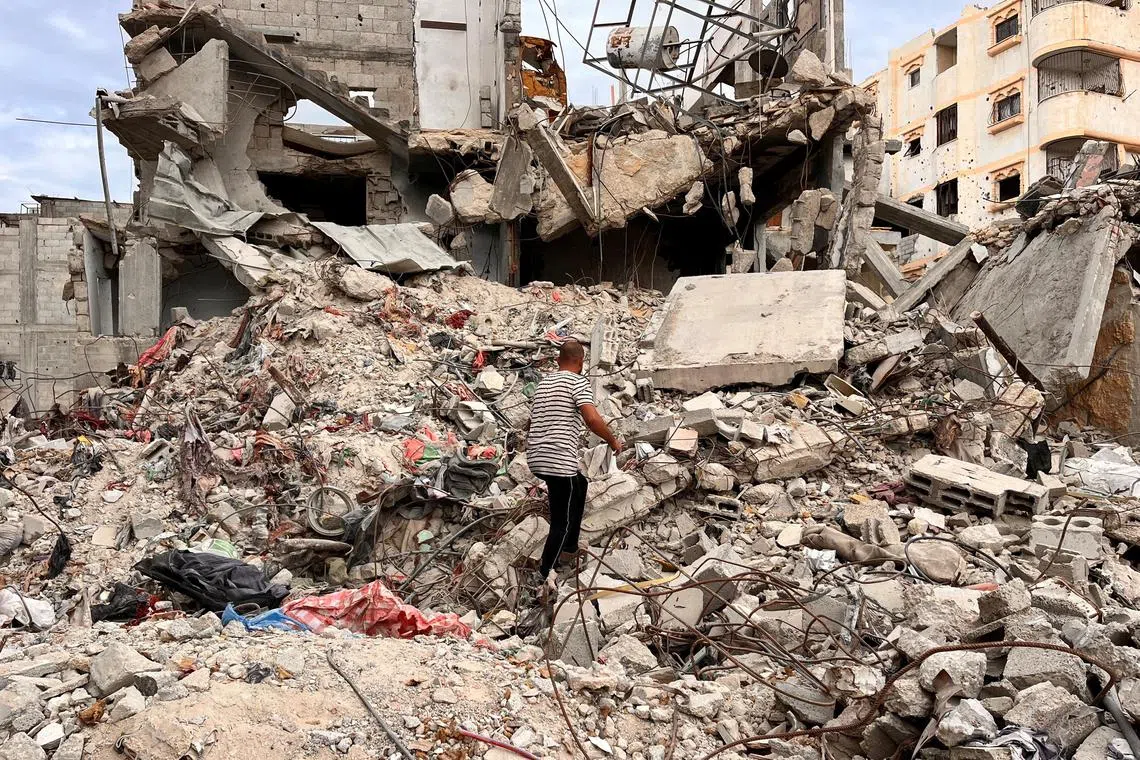 Palestinian Moein Abu Odeh searches for clothes through the rubble of a house destroyed in the Israeli military offensive, in Khan Younis in the southern Gaza Strip.