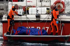 Rescue personnel stand near the body of a person in a bodybag at the scene where a luxury yacht sank, off the coast of Porticello, near the Sicilian city of Palermo, Italy.