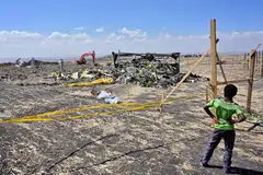 A boy looks on as forensic investigators comb the ground for DNA evidence near a pile of twisted airplane debris at the crash site of an Ethiopian airways operated Boeing 737 MAX aircraft at Hama Quntushele village in Oromia, Ethiopia, March 16, 2019.