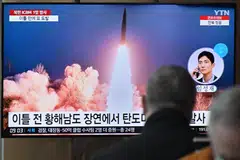 People sit near a television showing a news broadcast with file footage of a North Korean missile test in Seoul, March 16, 2023. 