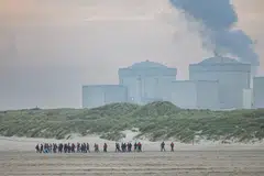 Migrants run from the dunes near Gravelines Nuclear Power Station across a beach to attempt to board smugglers' boats bound for Britain, in Gravelines, northern France on June 12, 2023. At dawn on June 12, 2023 on the beach of Gravelines, at least 180 migrants and 15 smugglers braved police patrols along the beachfront and attempted to board boats bound for Britain, only to be intercepted by police a few metres from the water's edge.