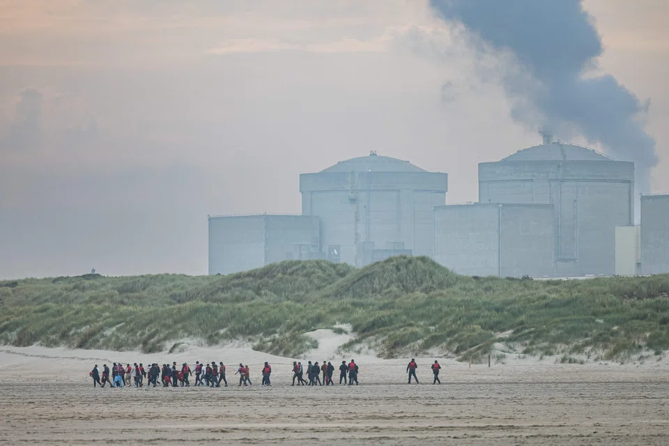 Migrants run from the dunes near Gravelines Nuclear Power Station across a beach to attempt to board smugglers' boats bound for Britain, in Gravelines, northern France on June 12, 2023. At dawn on June 12, 2023 on the beach of Gravelines, at least 180 migrants and 15 smugglers braved police patrols along the beachfront and attempted to board boats bound for Britain, only to be intercepted by police a few metres from the water's edge.