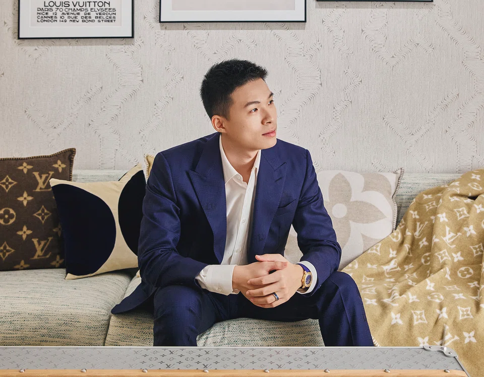 Soh Jun Wei wears a Louis Vuitton cream white shirt, navy blue suit, ring and Escale rose gold in blue dial watch.