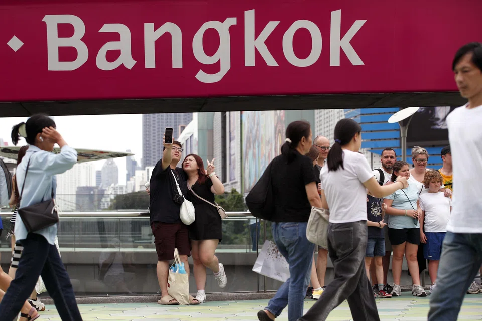 Foreign tourists take photographs at a shopping district in Bangkok, Thailand, Feb 24, 2025. 