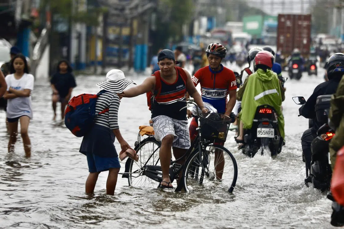 Pedestrians and motorists make their way through the water on a flooded road in Meycauayan, Bulacan, Philippines in the wake of typhoon Gaemi in July. Asean countries such as the Philippines are among the most vulnerable to climate risks.