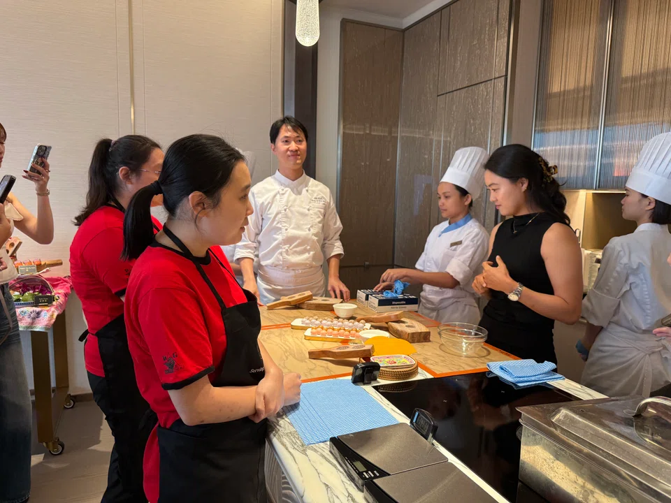 Metta School alumni Shirley Heng (left) and Rachel Tan (second from left) are joined by professional golfer Minjee Lee (in black) to learn how to make kueh from MBS chef Hoi Kuok I (centre, in white).