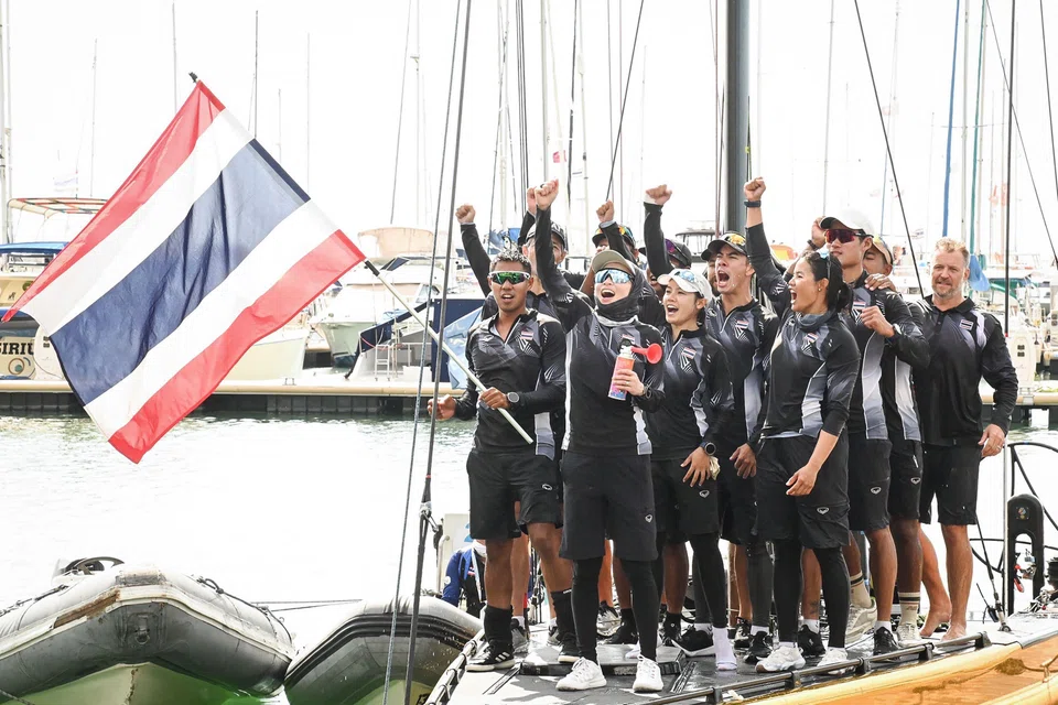 Thailand's Queen Suthida (centre) celebrating with her team after winning the gold medal in the mixed keelboat SSL47 sailing event during the 33rd SEA Games.