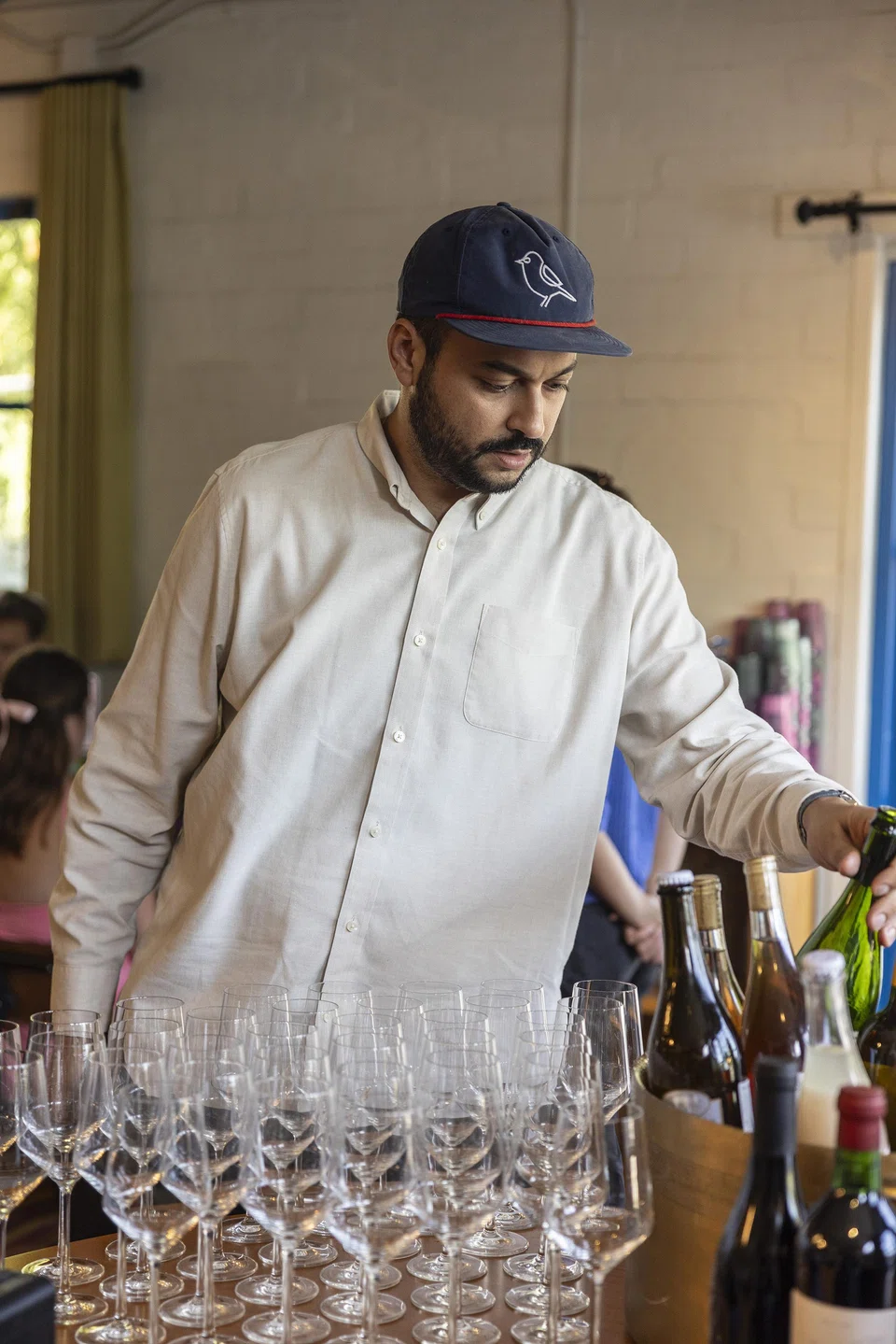 Arjav Ezekiel prepares wine at Birdie's, his restaurant in Austin, Texas on Aug 6, 2024. Ezekiel rose through the restaurant ranks, becoming a sommelier and opening Birdie's but few knew of his past as an undocumented immigrant. 