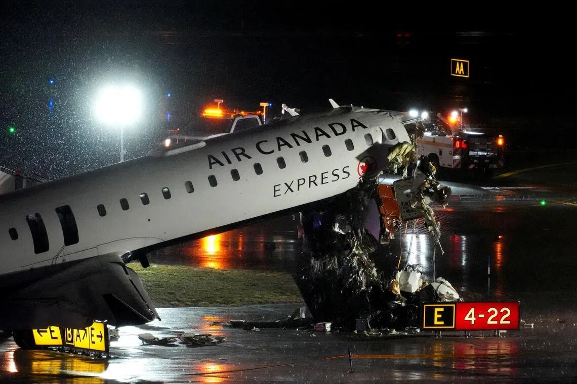 Debris hangs from a damaged Air Canada Express jet that collided with a fire truck at New York's LaGuardia Airport on Mar 23.