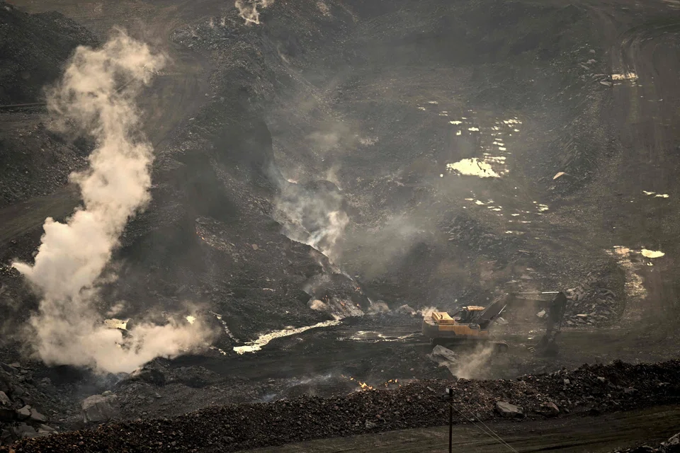 Smoke billows from an open-cast coal mine on the outskirts of Dhanbad in India's Jharkhand state on July 7, 2023. The underground fires in open-cast coal mines in eastern India have raged for over a century, blighting the lives of millions who depend on the dirty fuel for their livelihoods. 