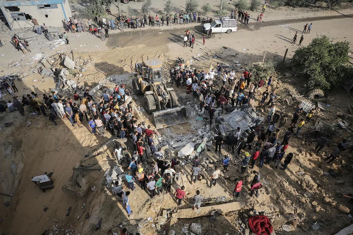 Palestinians search for survivors in the rubble of a residential building, in Khan Younis refugee camp in the southern Gaza Strip, on Oct 16.  