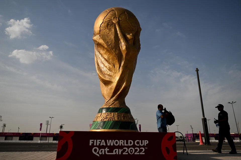 Men walk past a FIFA World Cup trophy replica outside the Ahmed bin Ali Stadium in Al-Rayyan on November 12, 2022, ahead of the Qatar 2022 FIFA World Cup football tournament.