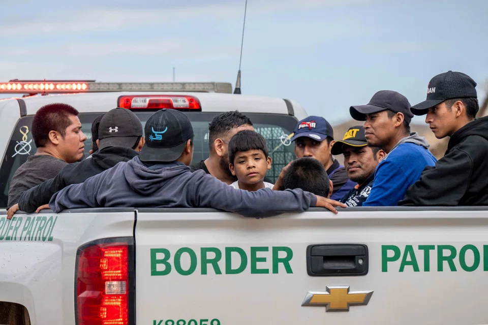 Migrants from Central and South America seeking asylum in the United States sit in the back of a border patrol vehicle after being apprehended by US Customs and Border protection officers after illegally crossing over into the US, Ruby, Arizona, June 24, 2024. 