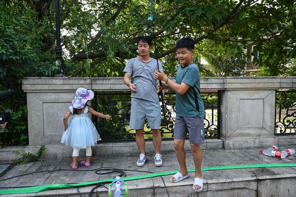 Stay-at-home dad Chen Hualiang plays with his daughter and son near their home in Shanghai, China, Aug 9, 2024.
