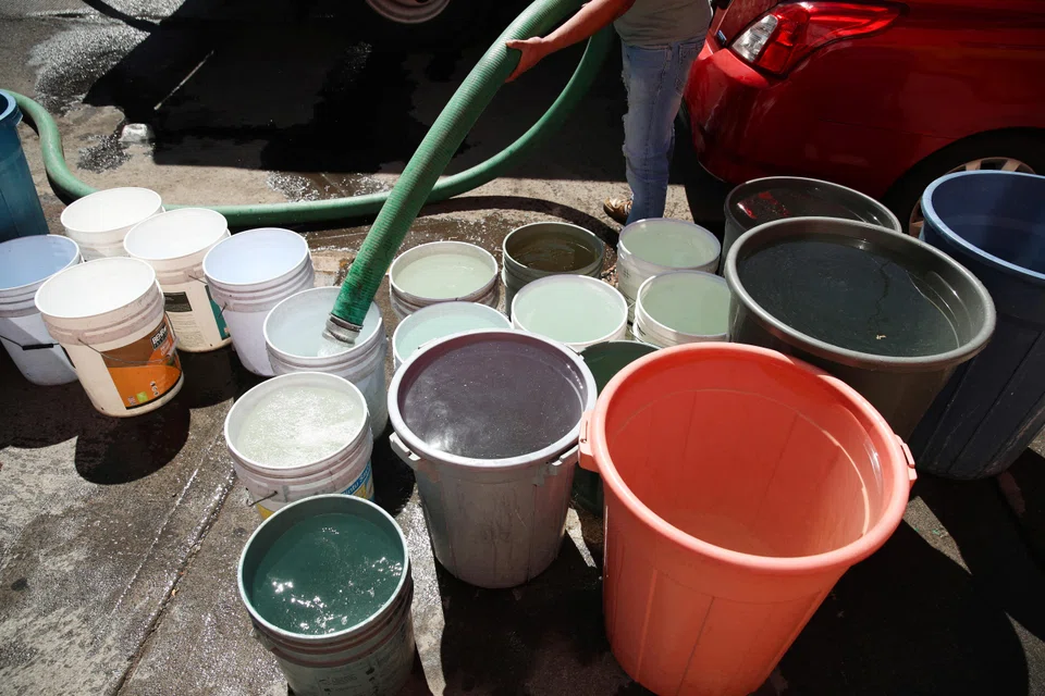 A person fills buckets and containers from a water tanker truck in Mexico City. The world is grappling with a global water crisis and more regions face the reality of a parched future.
