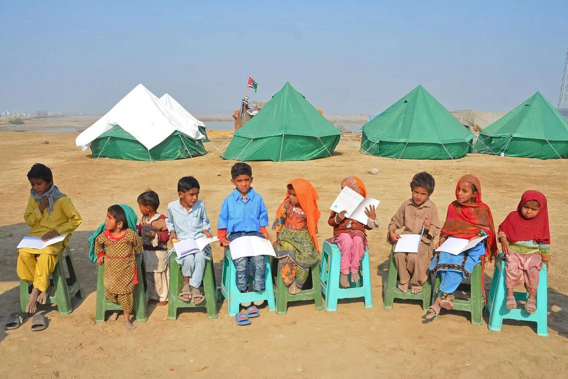 Displaced flood-affected children attend a mobile school class near a makeshift camp in the flood-hit area of Dera Allah Yar in Jaffarabad district of Pakistan's Balochistan province, Jan 9, 2023. 