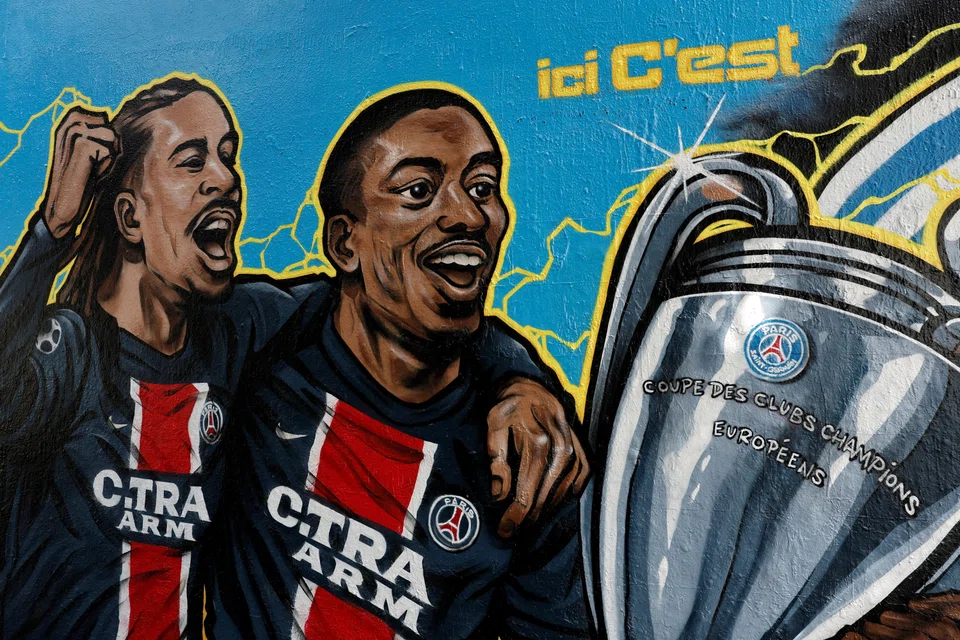 A street art mural in Paris shows PSG's Bradley Barcola (left) and Ousmane Dembele holding the Champions League trophy. PSG defeated Inter 5-0 in the June 1 final.