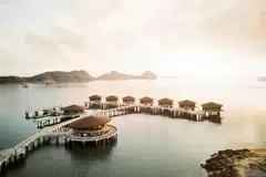 Overwater villas at Ta’aktana, Labuan Bajo, glowing in the sunset.