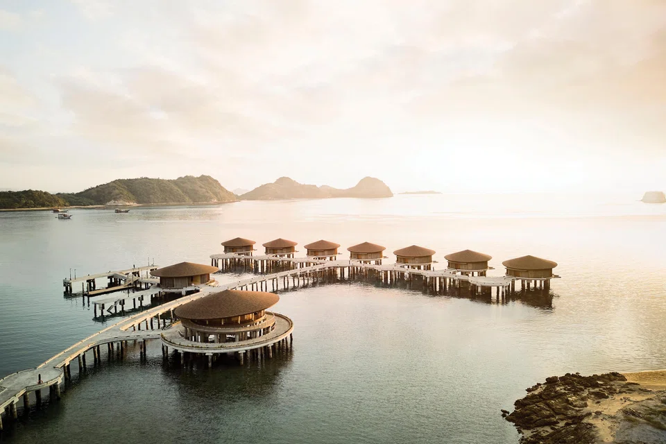 Overwater villas at Ta’aktana, Labuan Bajo, glowing in the sunset.