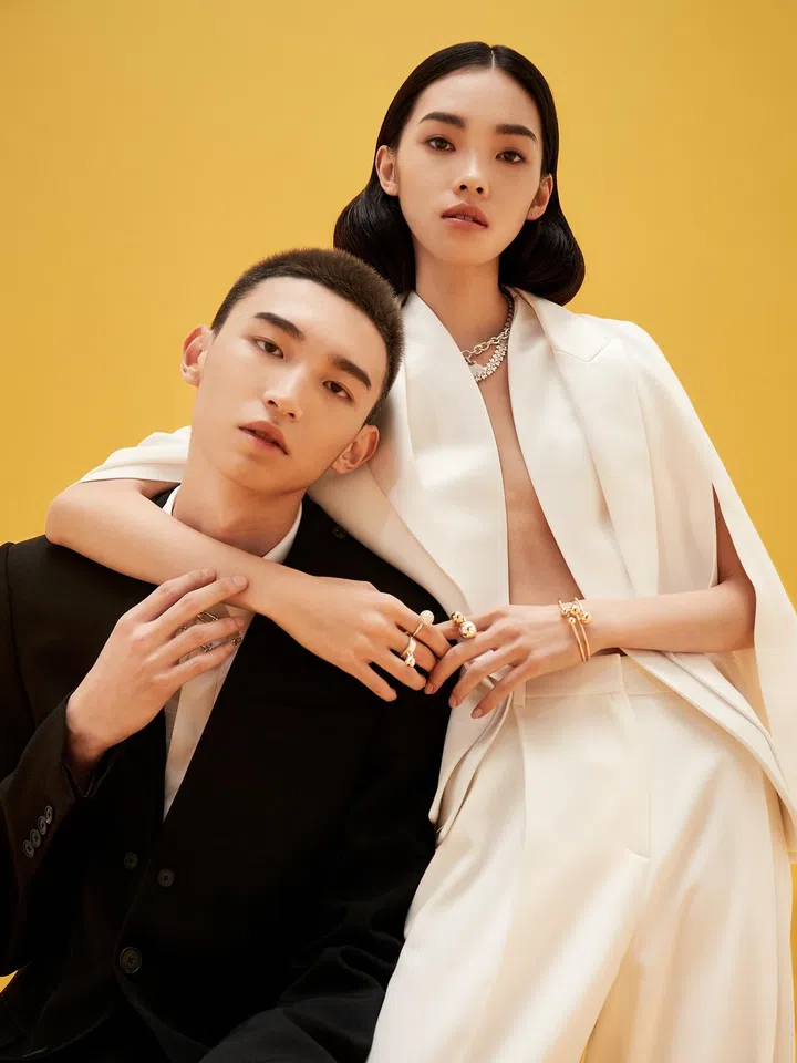 On him: Wool tuxedo jacket and cotton shirt, Givenchy. Hardwear necklaces in sterling silver and 18K yellow gold, and matching bracelets, Tiffany & Co. On her: Wool and satin cape jacket, and wool pants, Givenchy. (On right hand, from top) Hardwear 18K white gold ring with diamonds, matching sterling silver ring, (on neck, from top) Return To Tiffany Heart Tag Toggle sterling silver necklace, Platinum Marquise Diamond platinum necklace with diamonds, (on left hand, from left) Hardwear rings in 18K yellow gold and sterling silver, and matching bracelets in 18K yellow gold, Tiffany & Co. 
