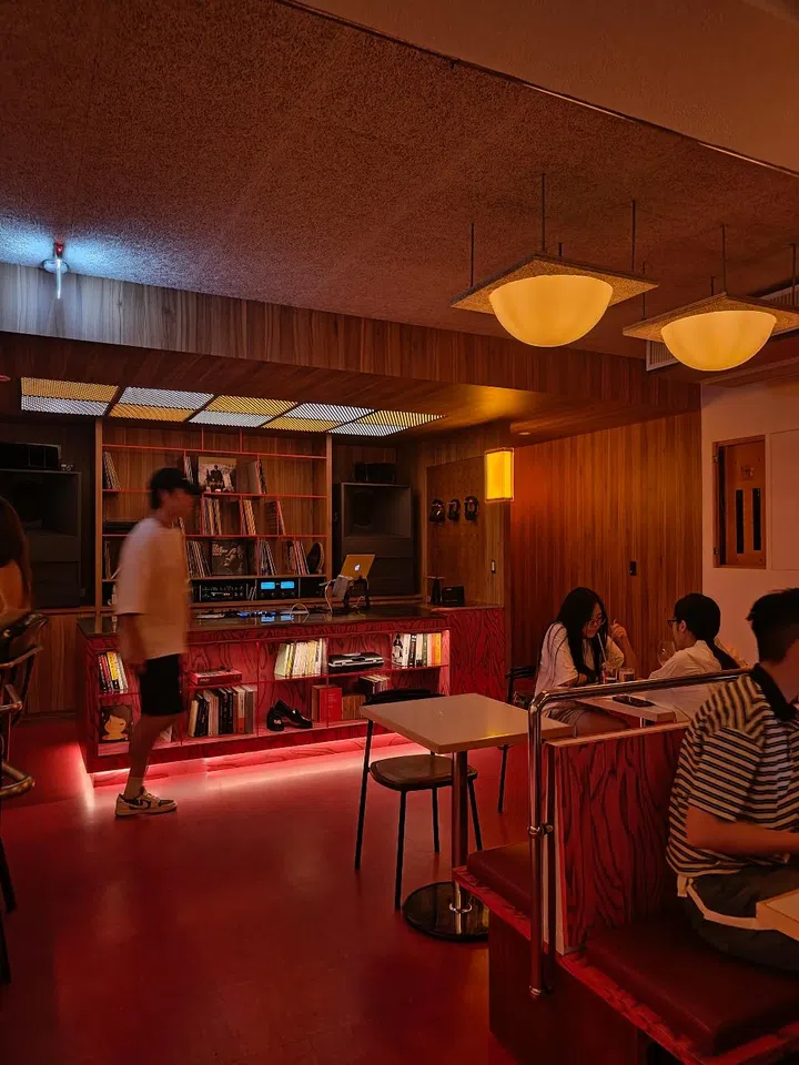  Interior of Hakuho (文心藝所) cafe in Taipei, showcasing modern architectural design with a sunlit reading area, minimalist wooden furniture, and industrial elements.