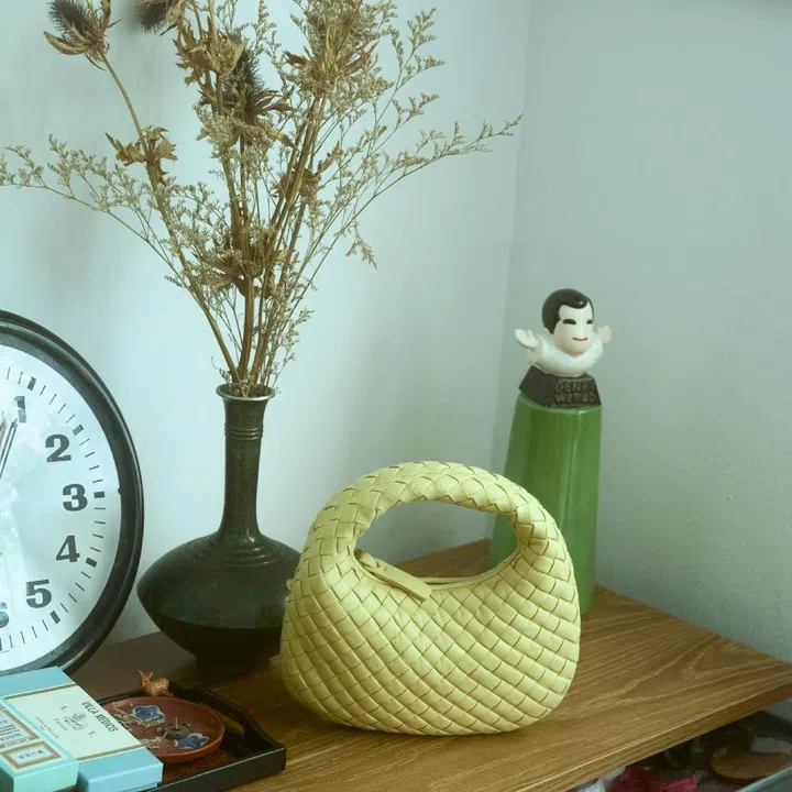 Bottega Veneta yellow Intrecciato Baby Veneta bag on a wooden shelf for an F ZINE artist craft story.