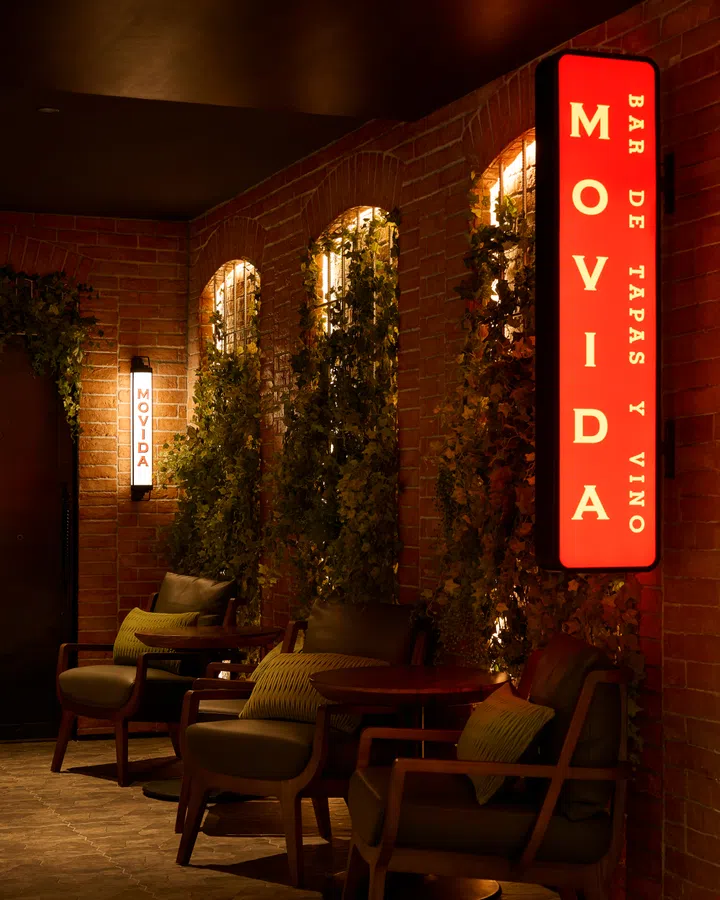 Interior of Movida Spanish restaurant at Raffles City Singapore with brick-red walls, stone ceiling and intimate dining space for tapas and wine