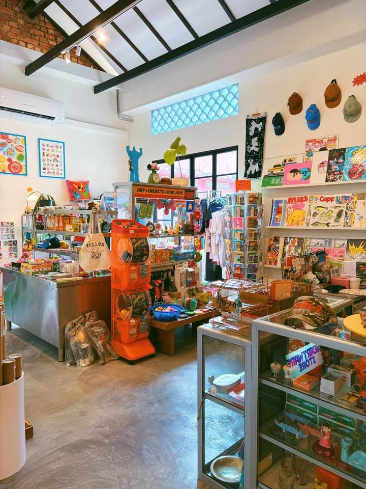 Interior view of Heartware Store & Gallery, a colorful lifestyle shop in Singapore featuring maximalist art prints, quirky collectibles, and a bright orange gashapon machine.