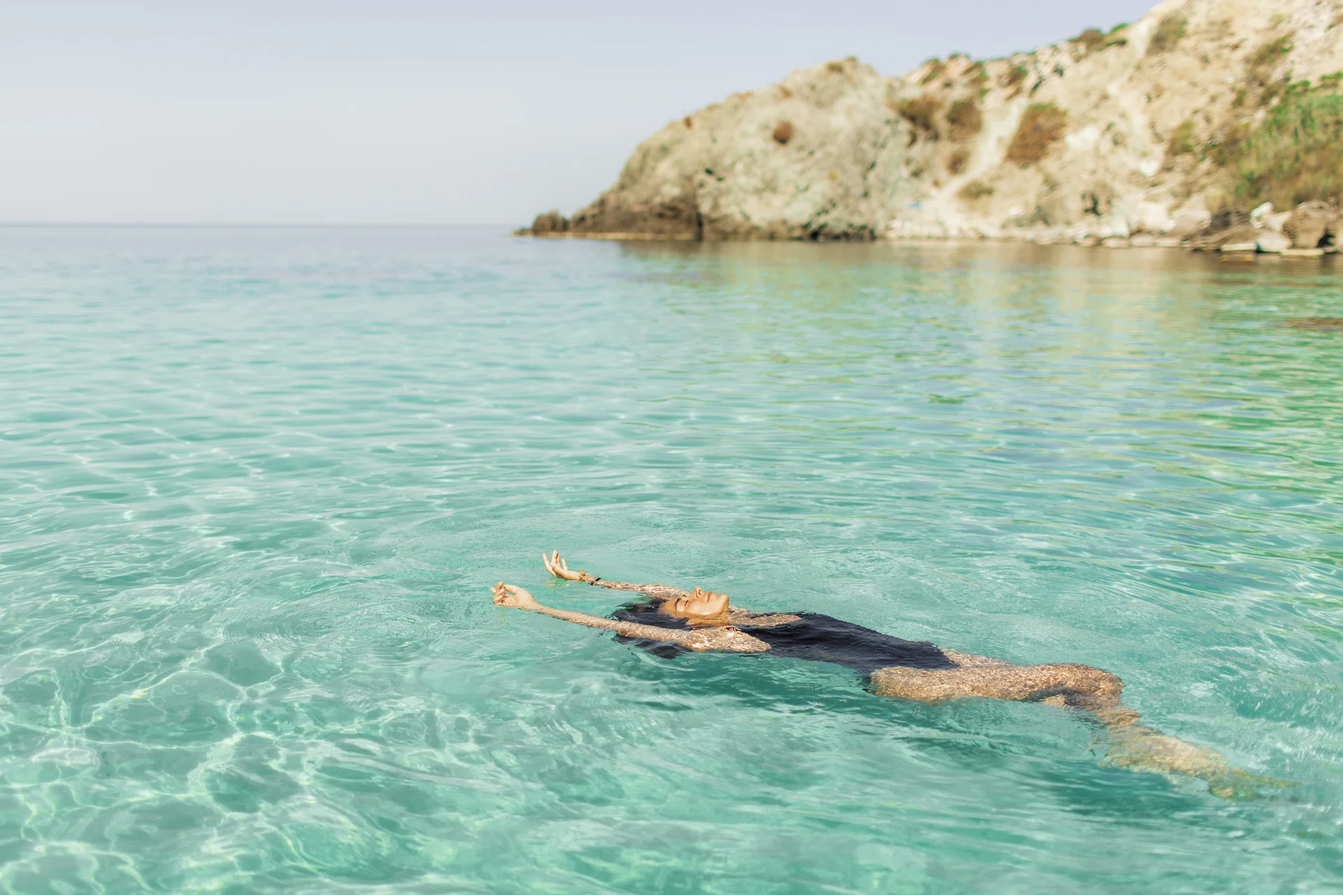 Brunette tanned girl in swimwear enjoying at beautiful turquoise colored water on tropical beach. Summer vacation, Beach Holiday and travel concept.