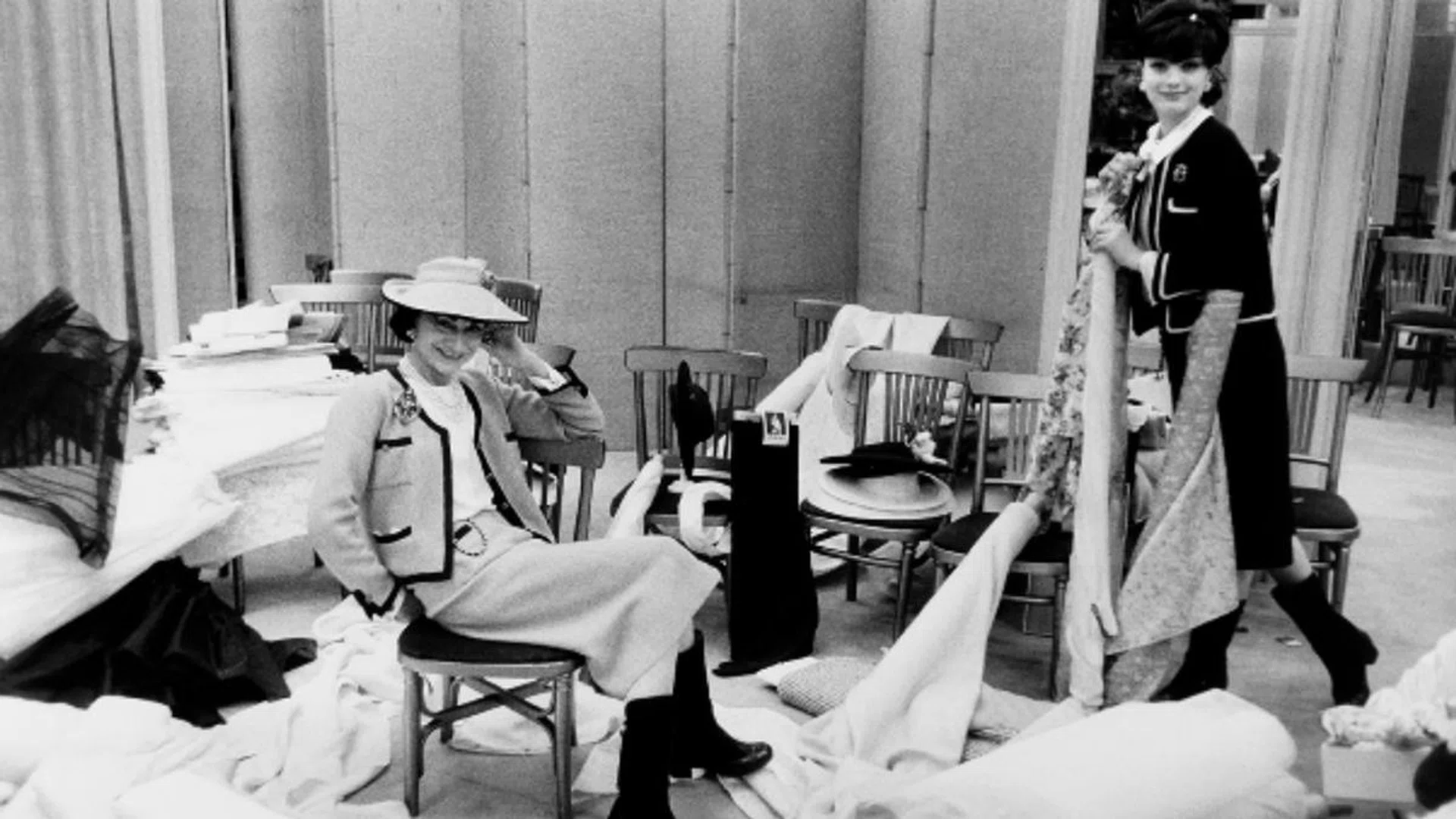 Gabrielle Chanel (left, pictured here with the model Marie-Helene Arnaud on right), an image of cool-meets-sophistication in her tweed skirt suit and knee-high boots in this photo taken in 1959. Credit: Willy Rizzo, Paris 1959 exhibited at the studio Willy Rizzo, Courtesy of Chanel